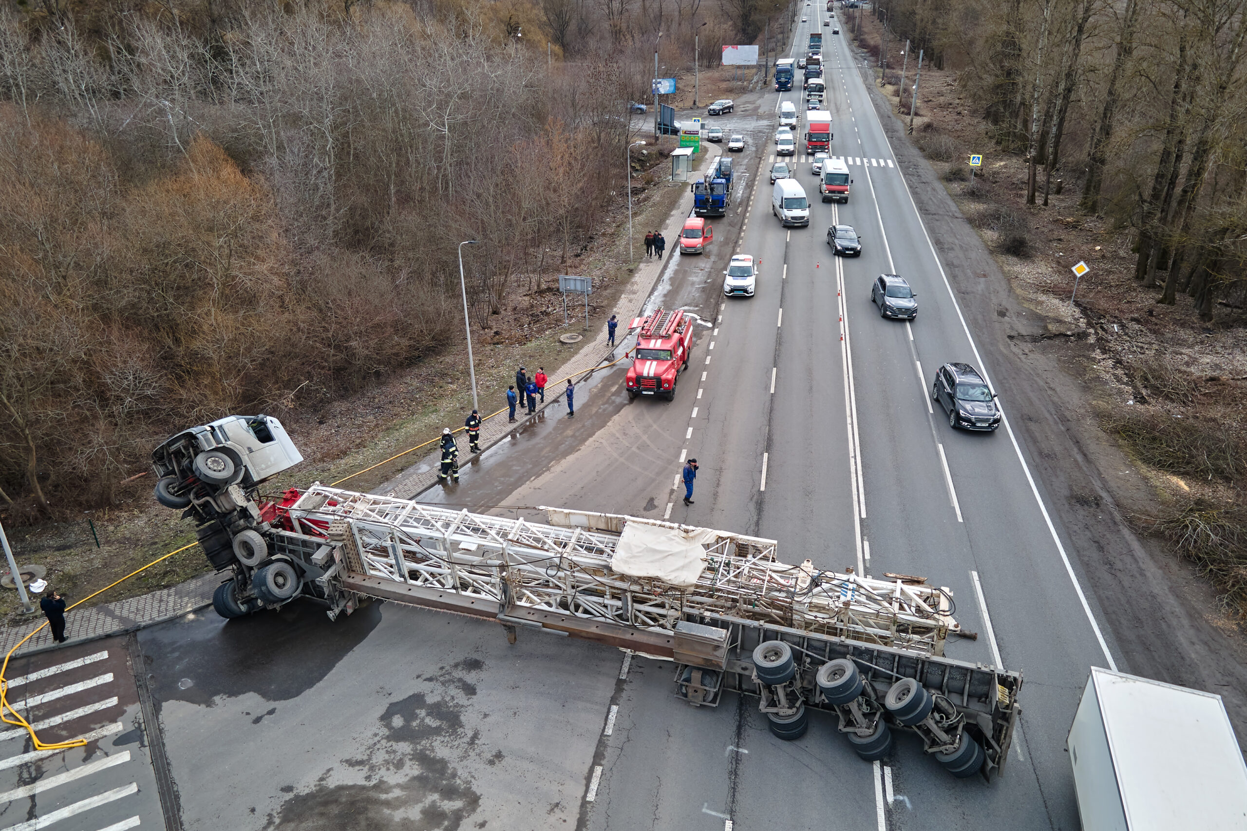 An overturned tractor-trailer blocks traffic in both directions on a four-lane highway.