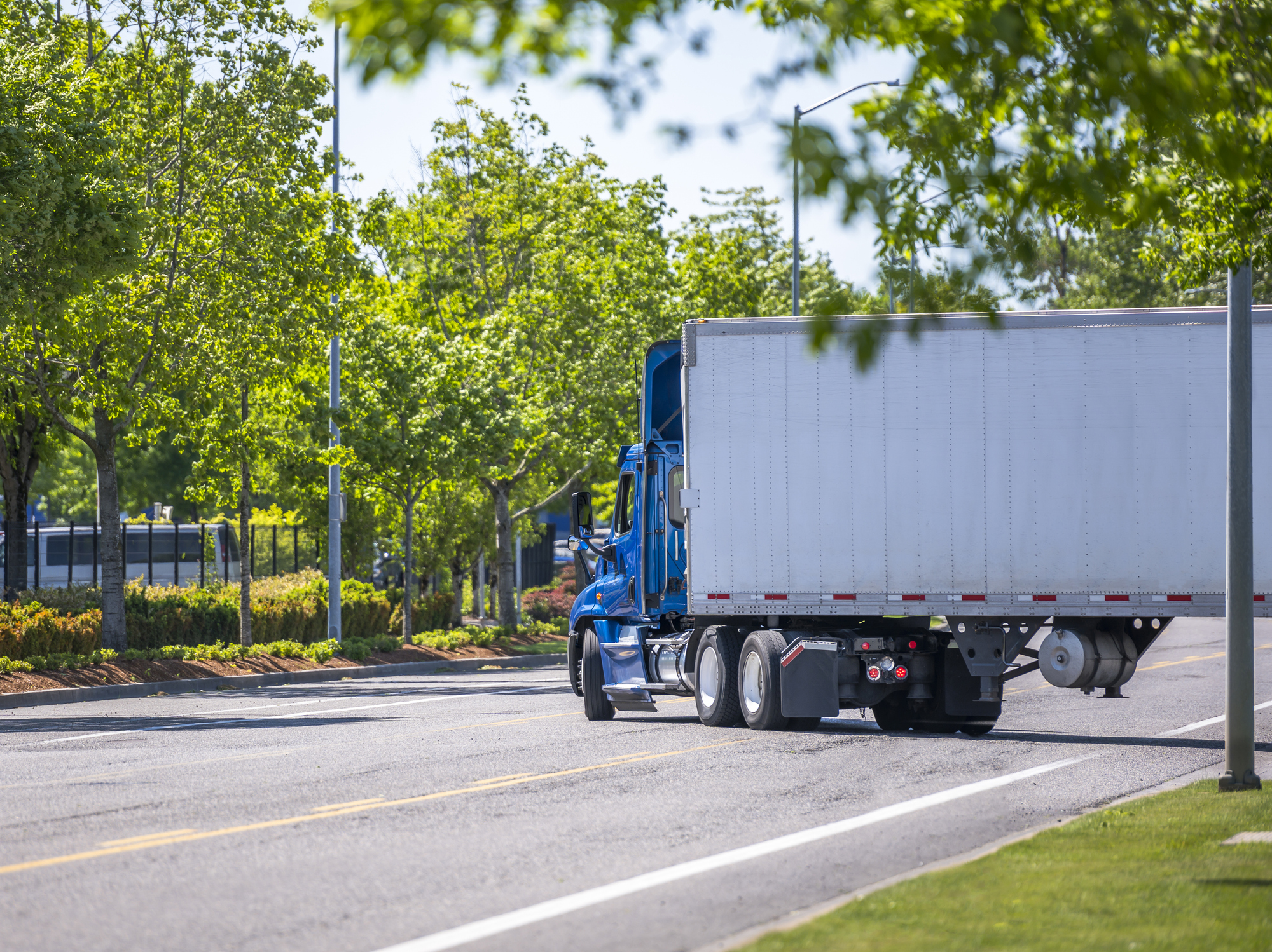 A semi-truck makes a wide right turn into traffic leaving a facility.