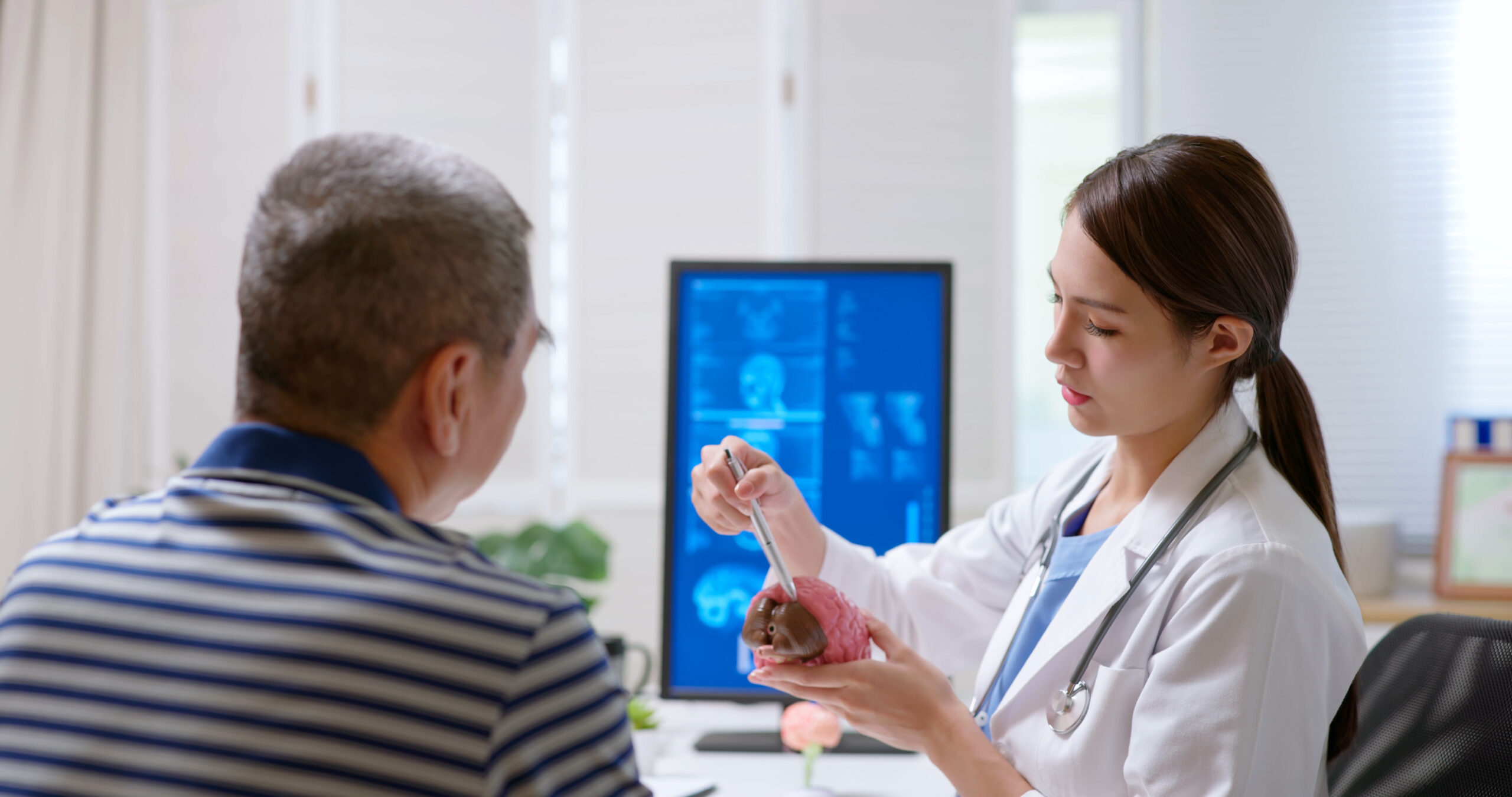 A doctor uses a model of the brain to explain the extent of the injury and the plan of treatment for a TBI patient.