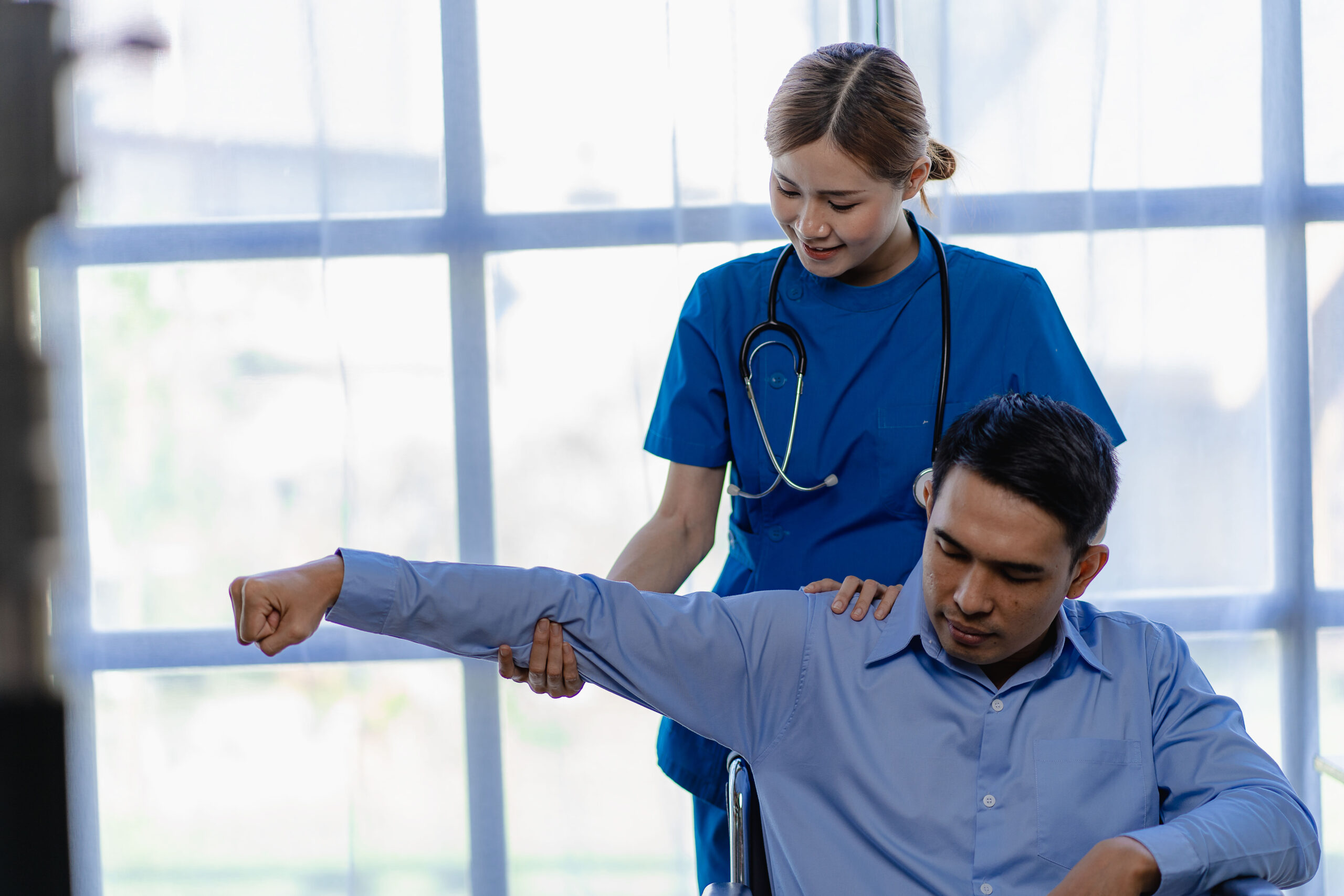 A female doctor performs physical therapy for a male patient in a wheelchair as he recovers from a personal injury. 