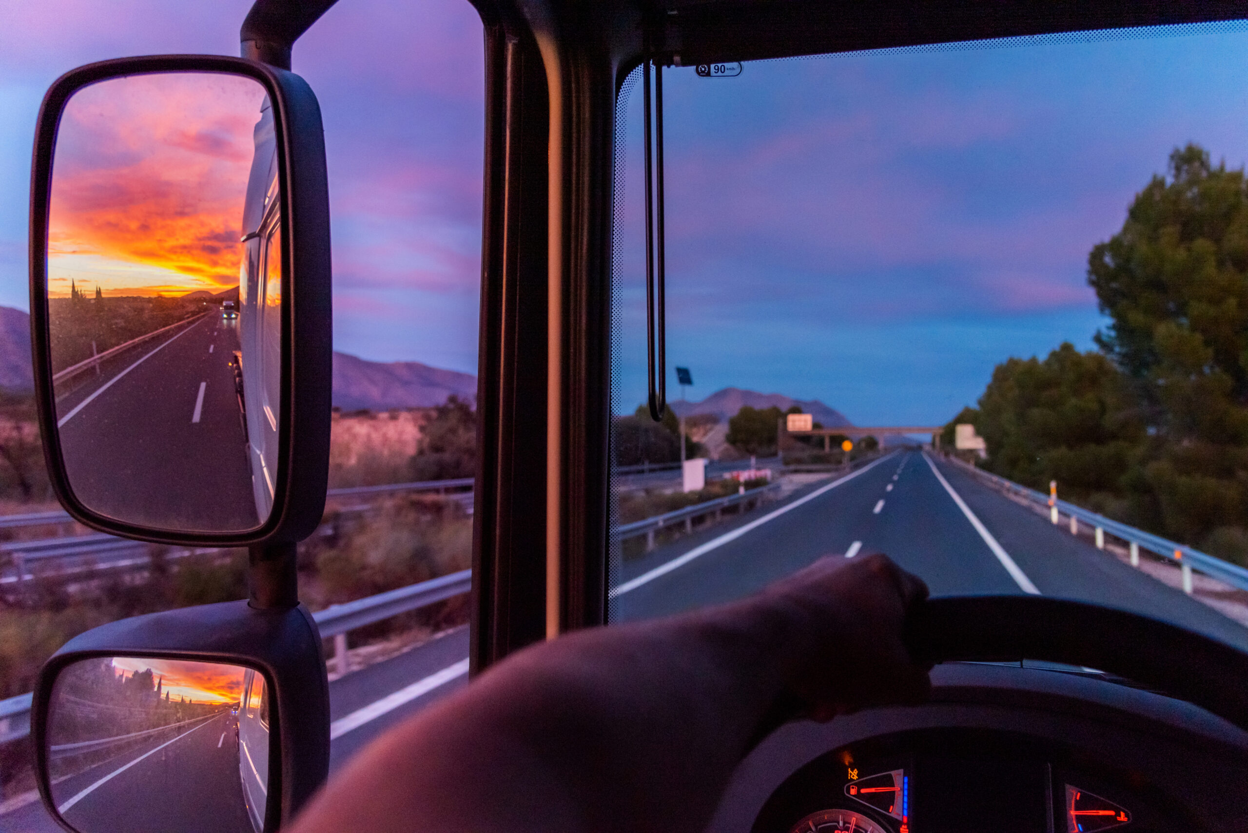 View of the highway from the driving position of a semi-truck.