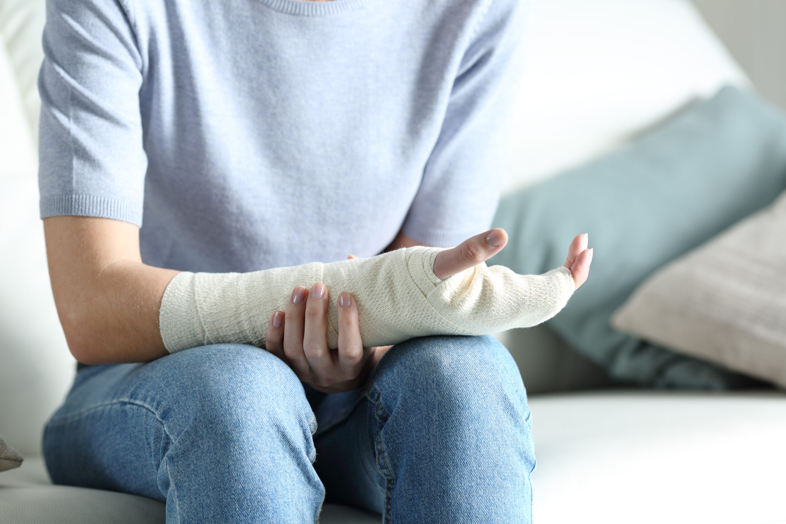 A woman gently holds her bandaged arm after being treated for severe burn injuries.